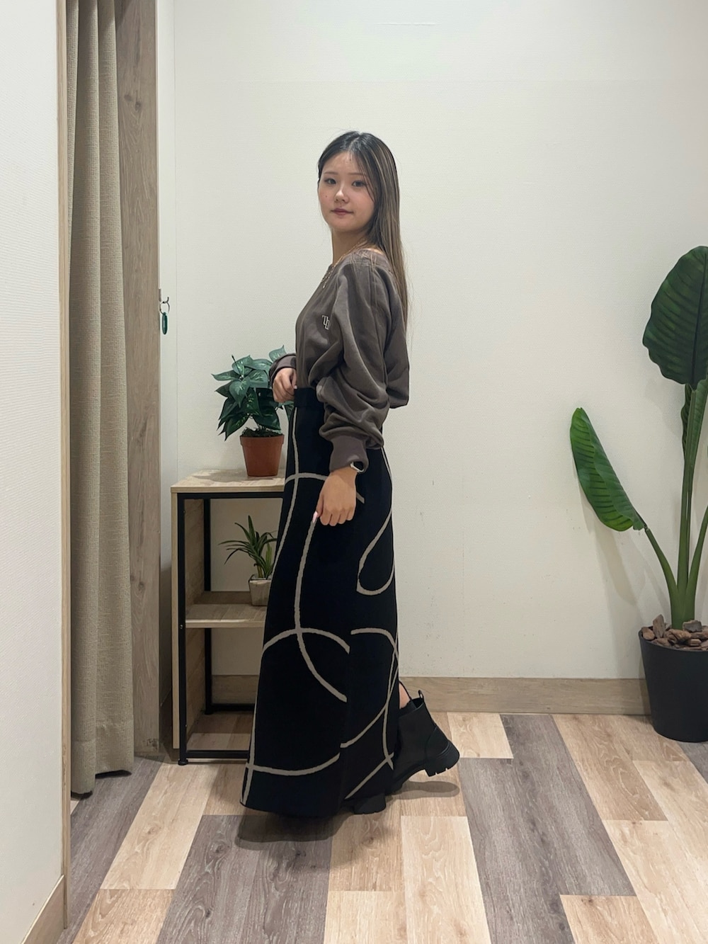 ブラック系のスカート、ブラウン系のTシャツ/カットソー、ブラック系のブーツを着用したレディースの秋コーディネートの5枚目の写真