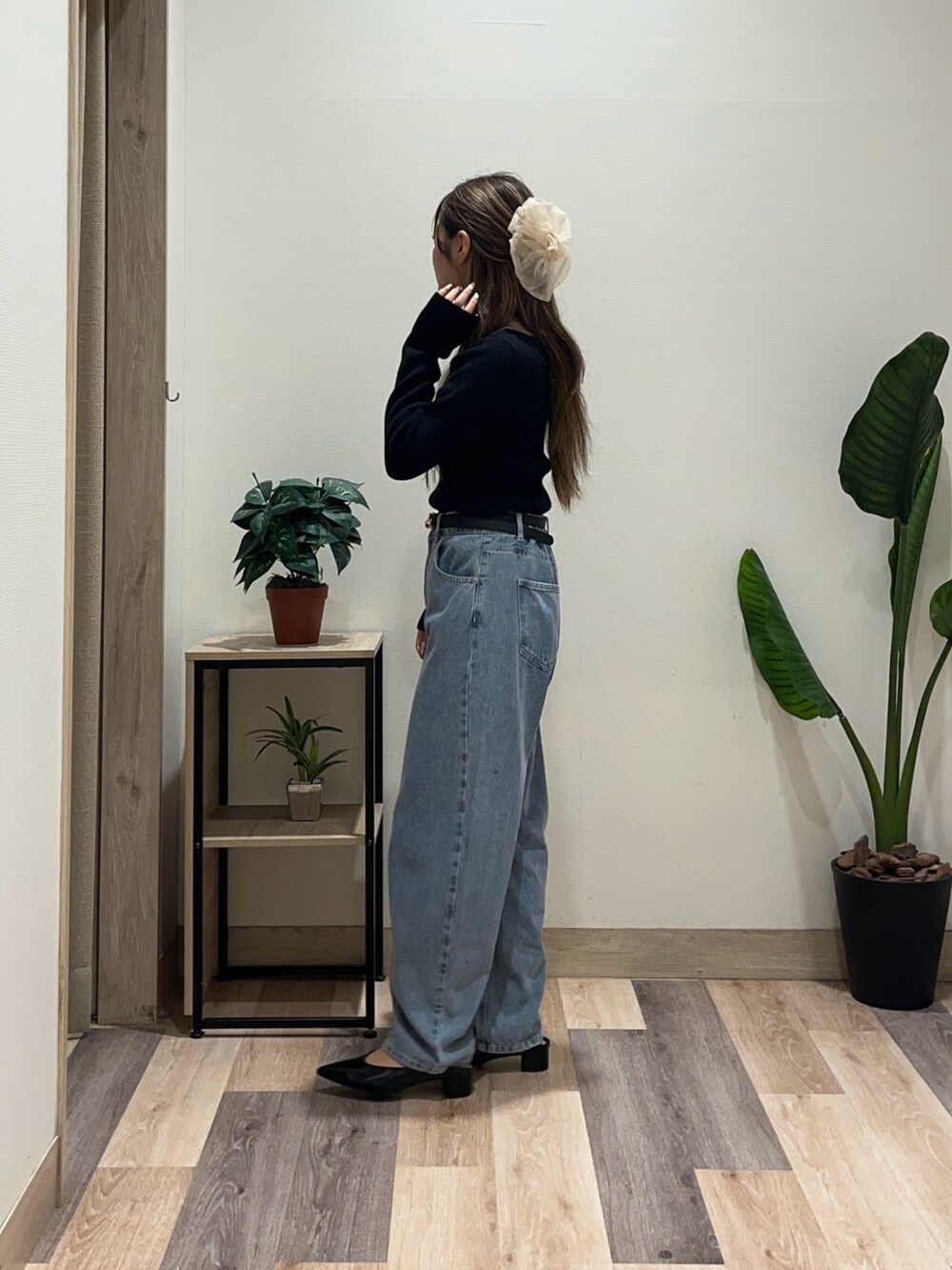 ブルー系のデニムパンツ、ブラック系のニット/セーター、ブラック系のベルトを着用したレディースの秋コーディネートの4枚目の写真