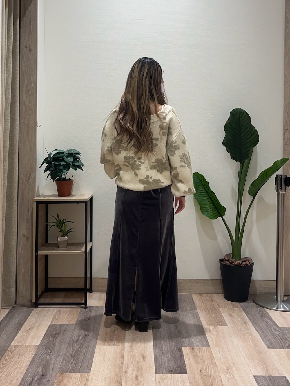 グレー系のスカート、ホワイト系のニット/セーター、ブラック系のブーツを着用したレディースの秋コーディネートの4枚目の写真