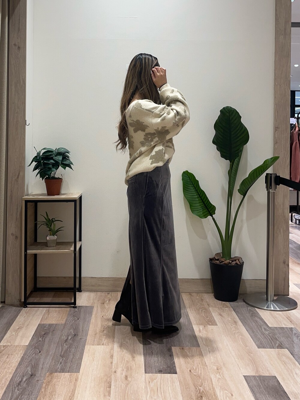 グレー系のスカート、ホワイト系のニット/セーター、ブラック系のブーツを着用したレディースの秋コーディネートの3枚目の写真