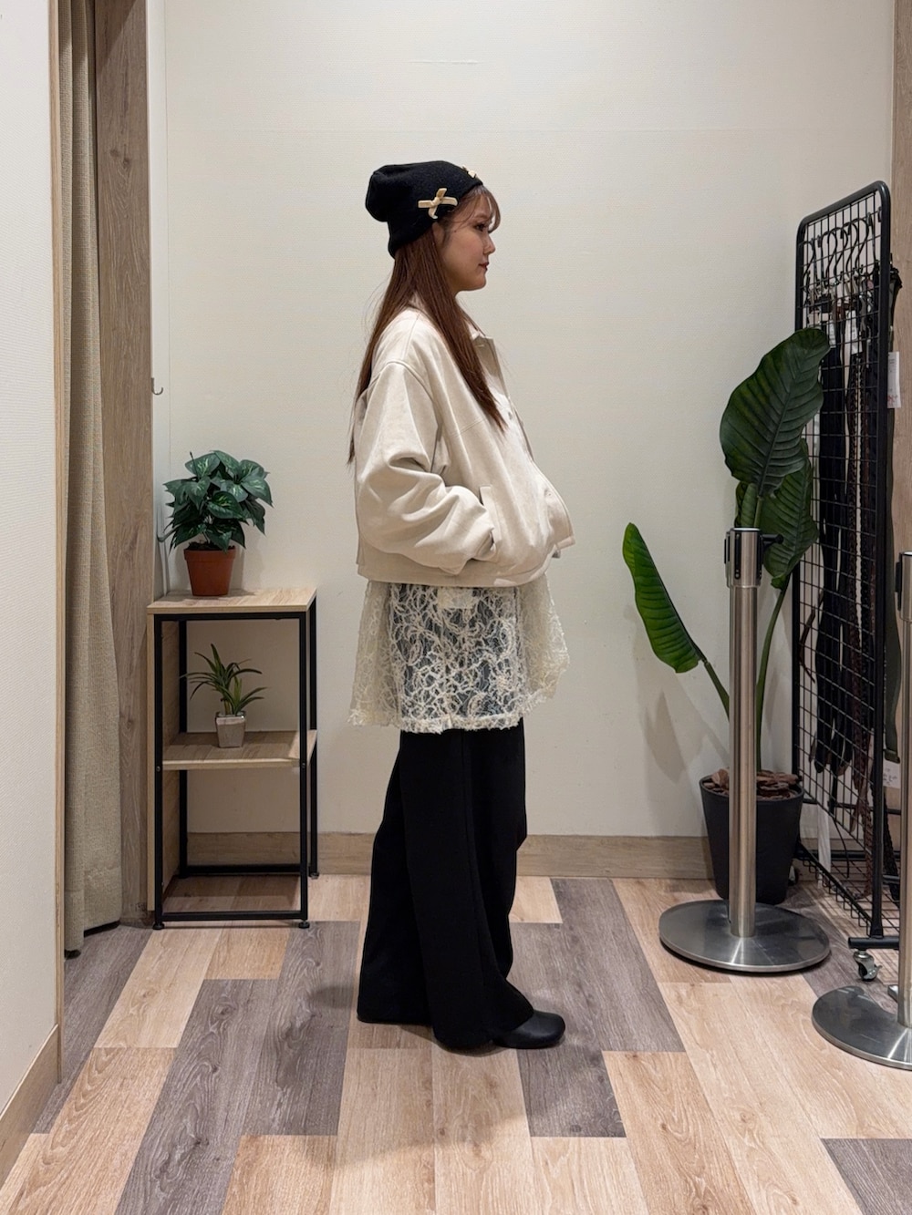 イエロー系のブルゾン、ブラック系のブーツ、ホワイト系のチュニックを着用したレディースの冬コーディネートの4枚目の写真