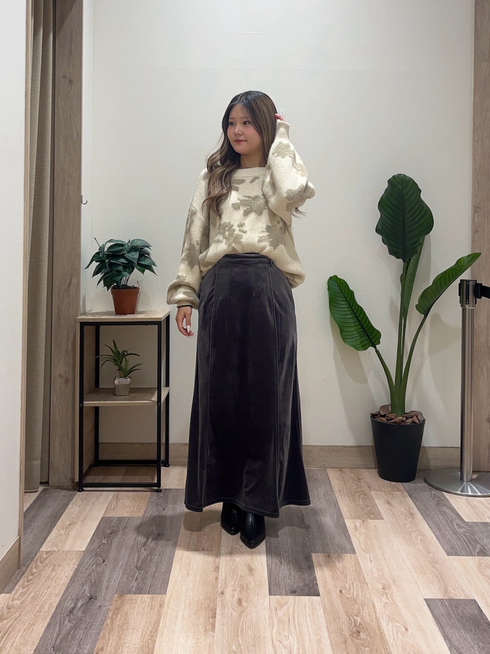 グレー系のスカート、ホワイト系のニット/セーター、ブラック系のブーツを着用したレディースの秋コーディネートの2枚目の写真