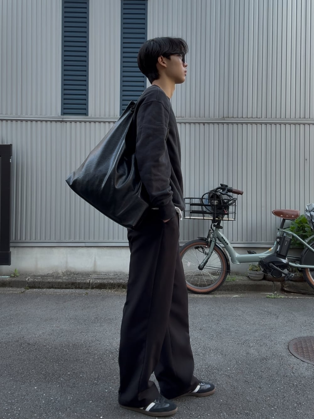 ブラック系のスラックス、ホワイト系のスニーカー、ブラック系のスウェットを着用したメンズの春コーディネートの2枚目の写真