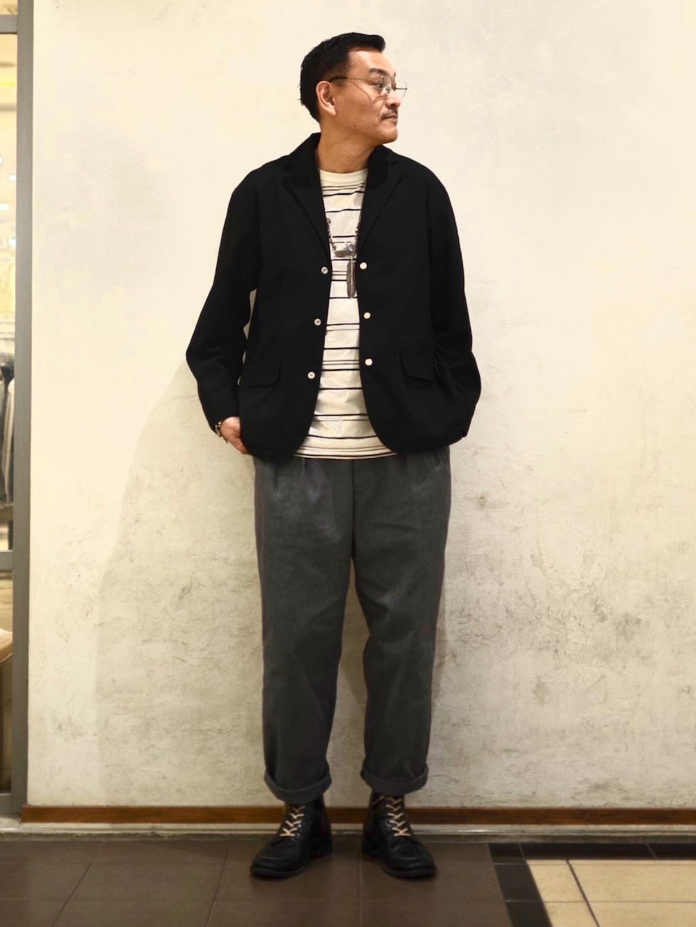 ブラック系のテーラードジャケット、ベージュ系のTシャツ/カットソー、グレー系のチノパンツを着用したメンズの冬コーディネートの2枚目の写真