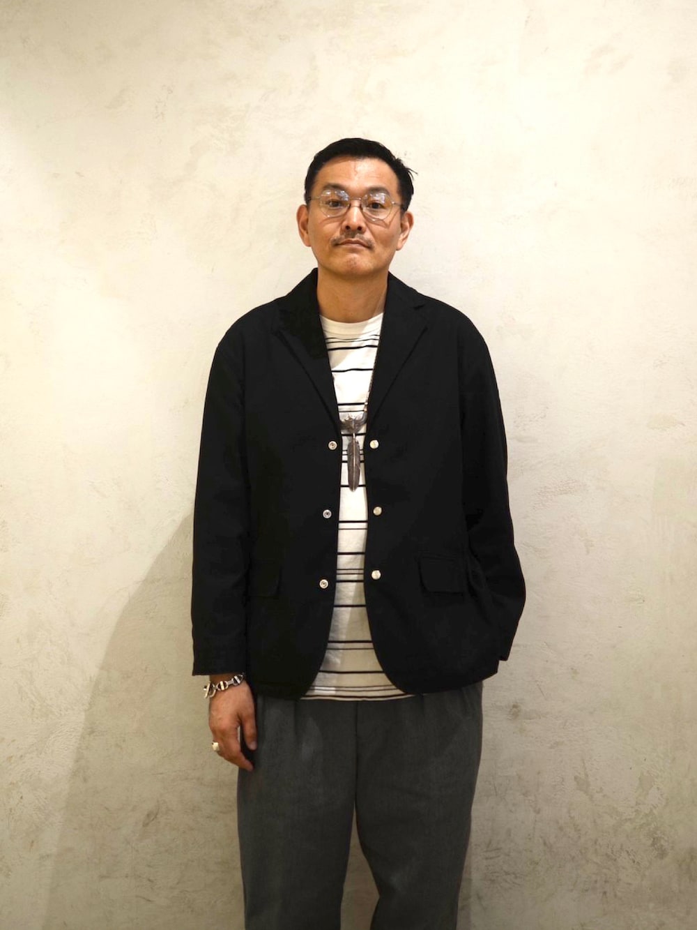 ブラック系のテーラードジャケット、ベージュ系のTシャツ/カットソー、グレー系のチノパンツを着用したメンズの冬コーディネートの5枚目の写真