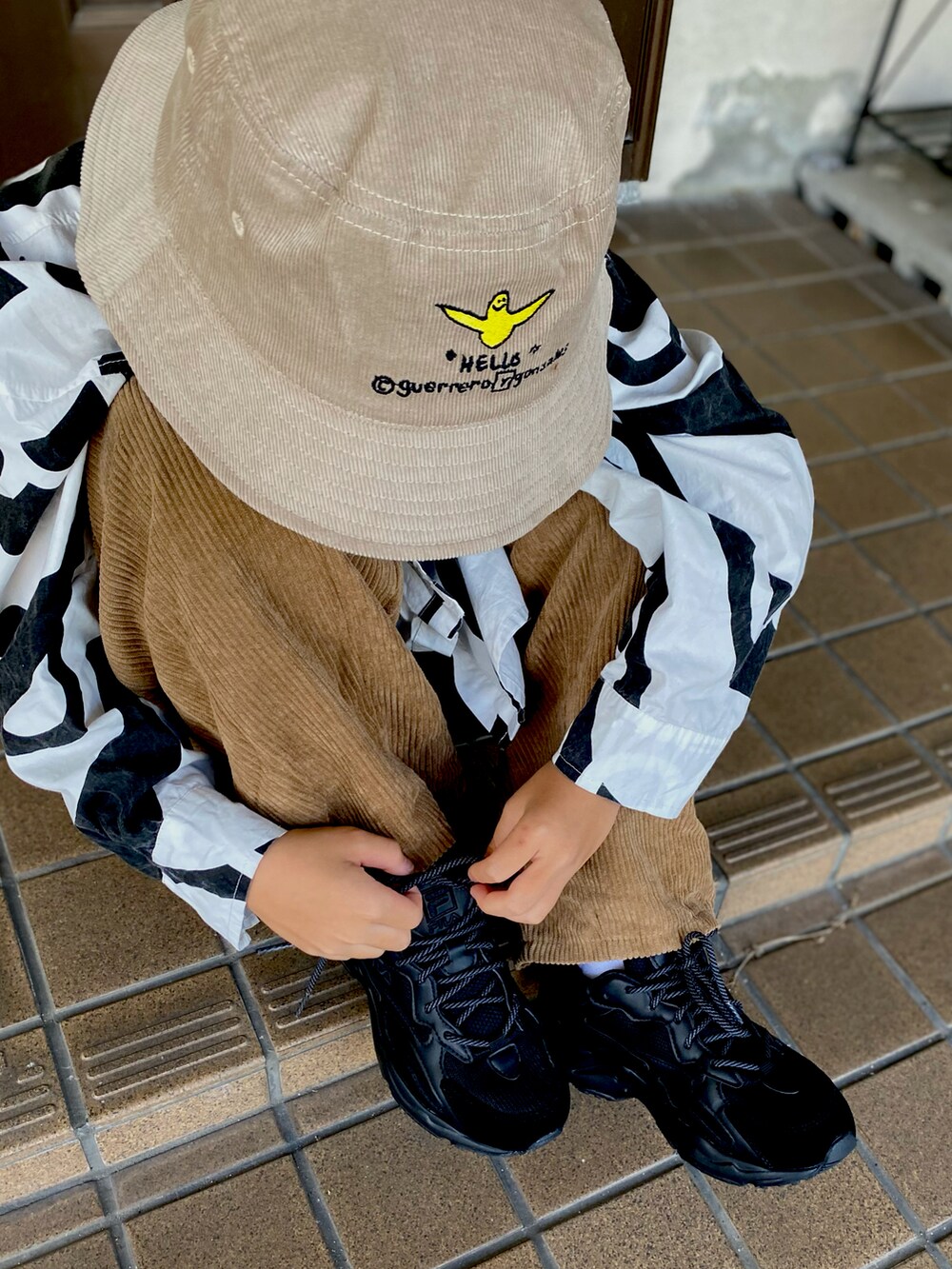 グレー系のスニーカー、ブラック系のショルダーバッグ、ベージュ系のその他パンツを着用したキッズの秋コーディネートの2枚目の写真