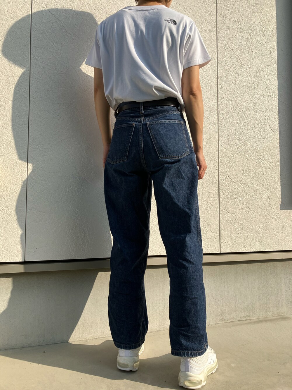 ホワイト系のTシャツ/カットソー、ブルー系のデニムパンツ、ホワイト系のスニーカーを着用したレディースの秋コーディネートの2枚目の写真