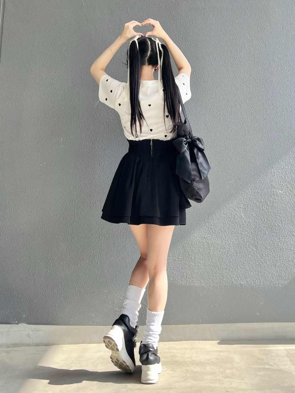 ブラック系のバッグ、ホワイト系のTシャツ/カットソー、ホワイト系のスニーカーを着用したレディースの夏コーディネートの3枚目の写真