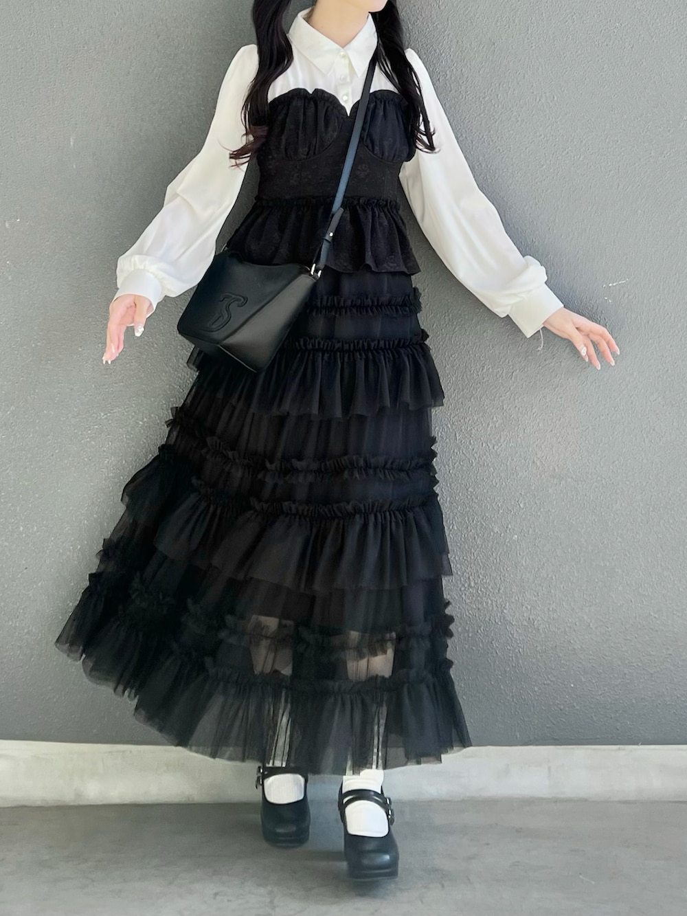 ブラック系のスカート、ブラック系のトップス、ブラック系のパンプスを着用したレディースの春コーディネートの2枚目の写真