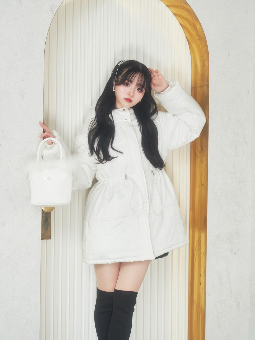 ホワイト系のジャケット/アウター、ホワイト系のバッグ、ブラック系のブーツを着用したレディースの冬コーディネートの2枚目の写真