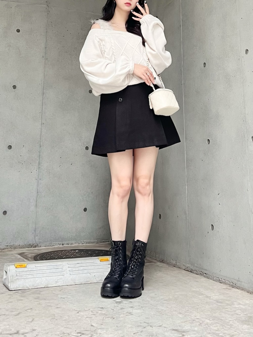 ホワイト系のニット/セーター、ブラック系のスカート、ブラック系のブーツを着用したレディースの秋コーディネートの3枚目の写真