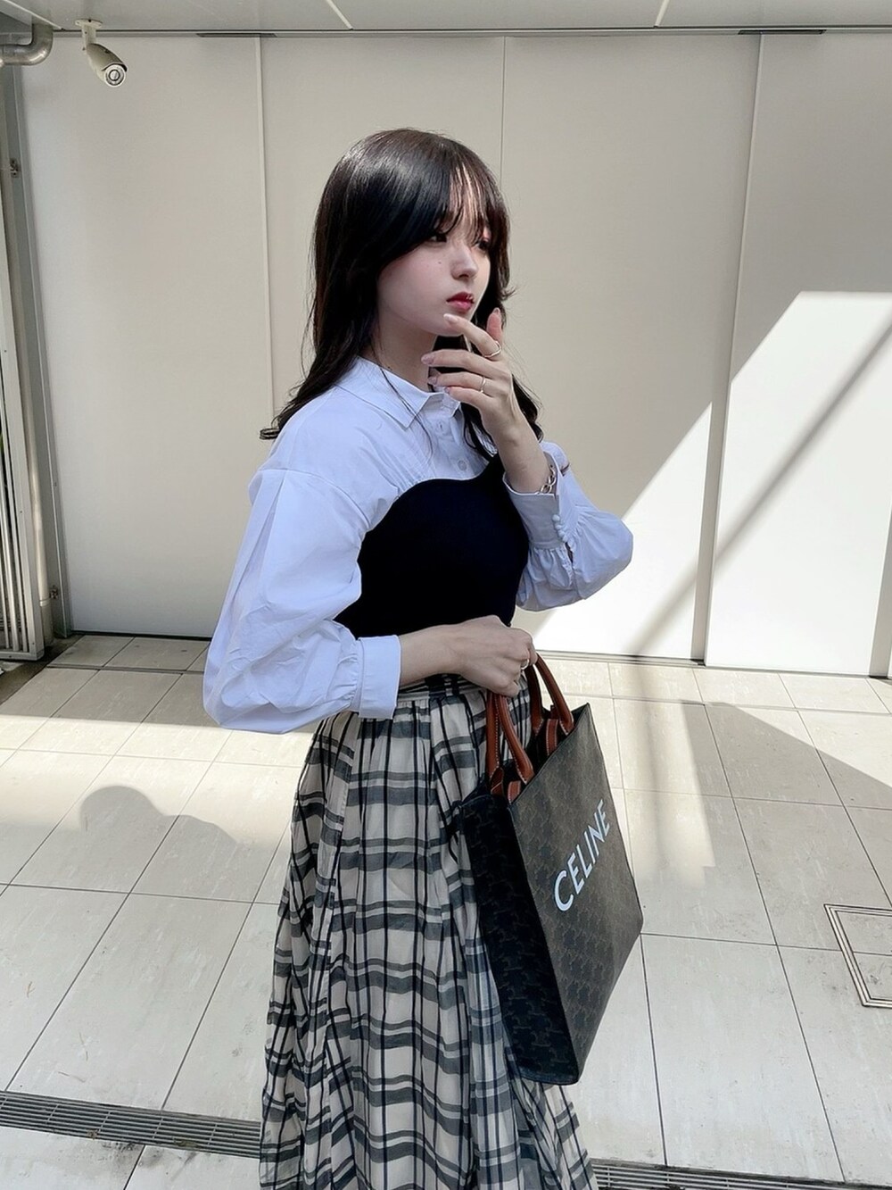 ブラック系のニット/セーター、ホワイト系のスカートを着用したレディースの春コーディネートの4枚目の写真