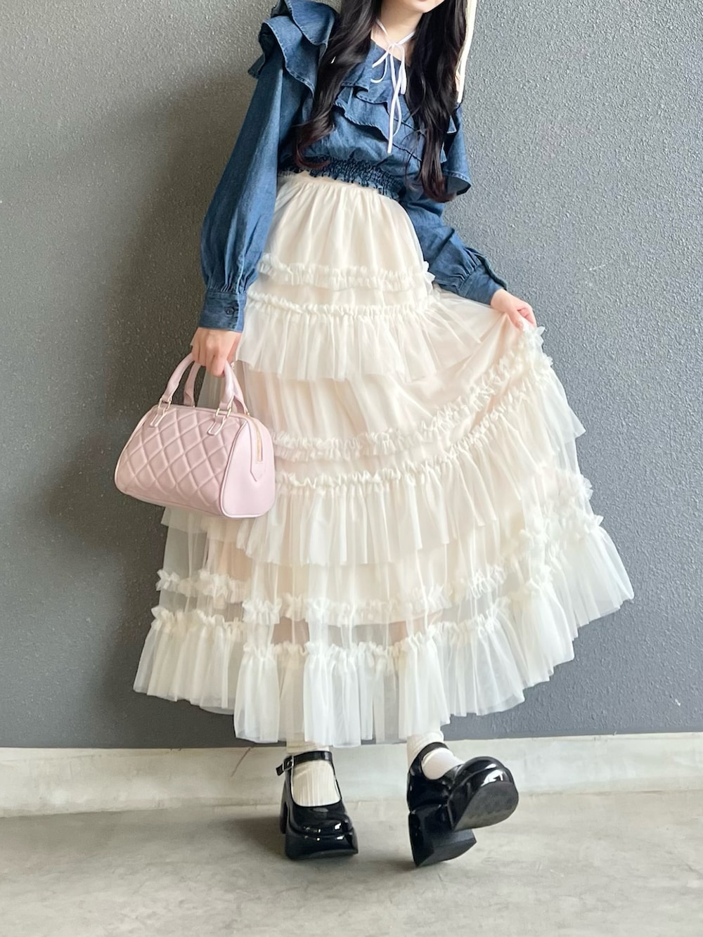 ブラック系のパンプス、ホワイト系のスカート、ピンク系のバッグを着用したレディースの春コーディネートの2枚目の写真