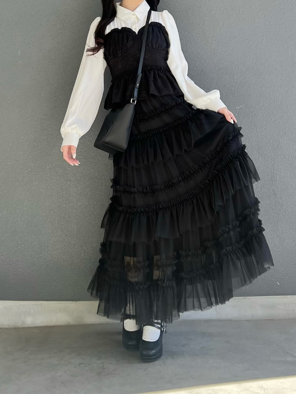 ブラック系のスカート、ブラック系のトップス、ブラック系のパンプスを着用したレディースの春コーディネートの4枚目の写真