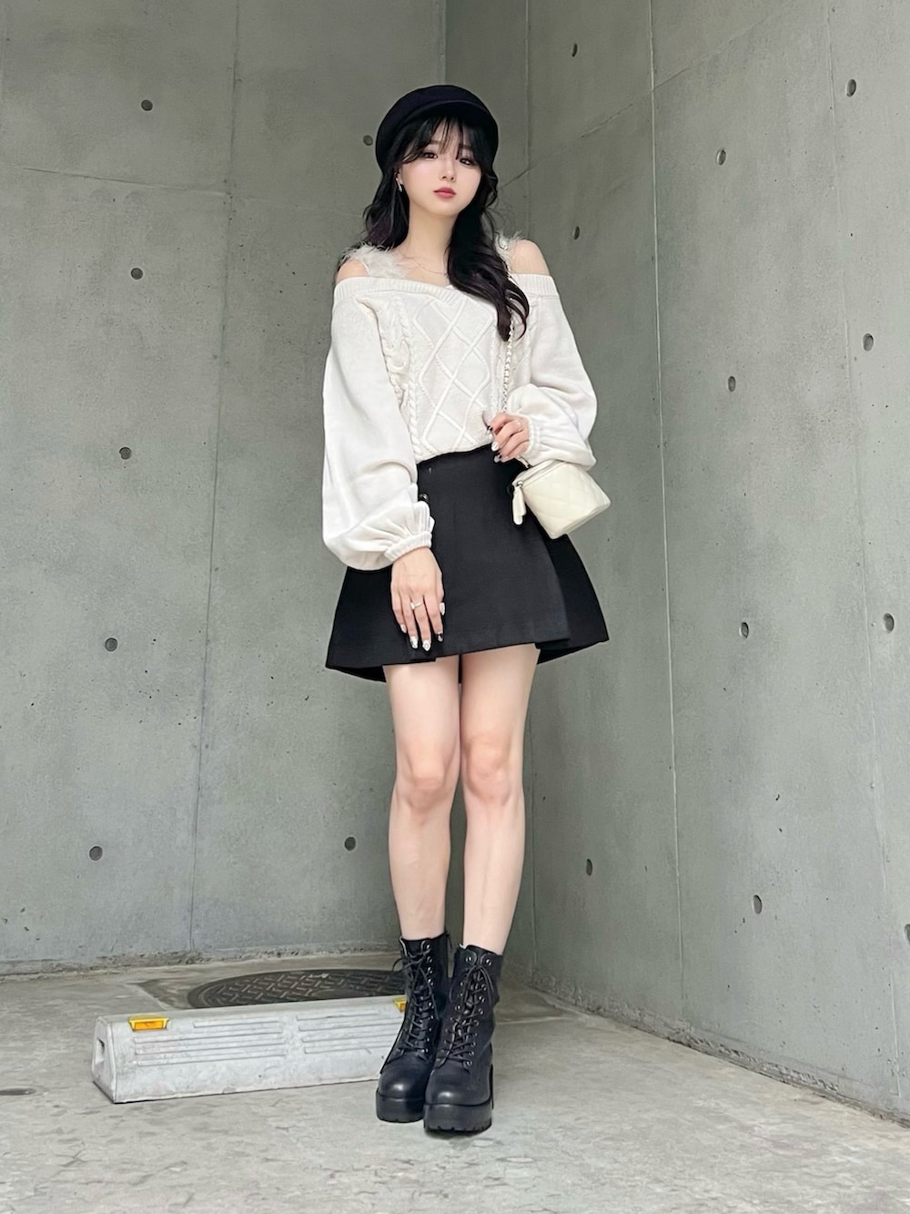 ホワイト系のニット/セーター、ブラック系のスカート、ブラック系のブーツを着用したレディースの秋コーディネートの2枚目の写真