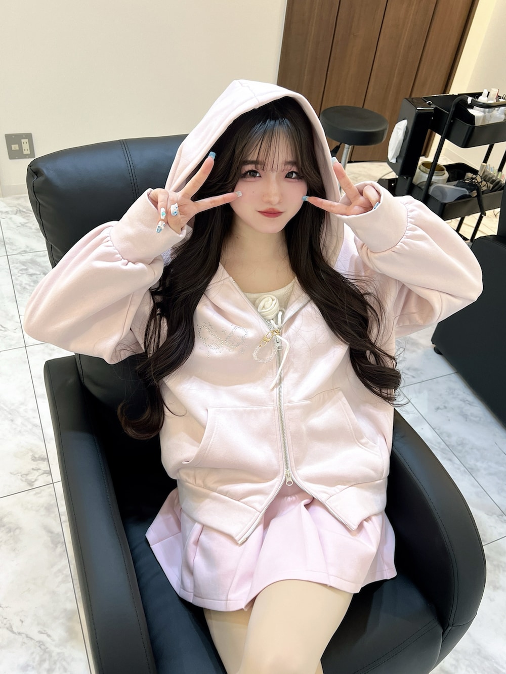 ピンク系のパーカー、ホワイト系のショルダーバッグ、ホワイト系のスニーカーを着用したレディースの春コーディネートの5枚目の写真