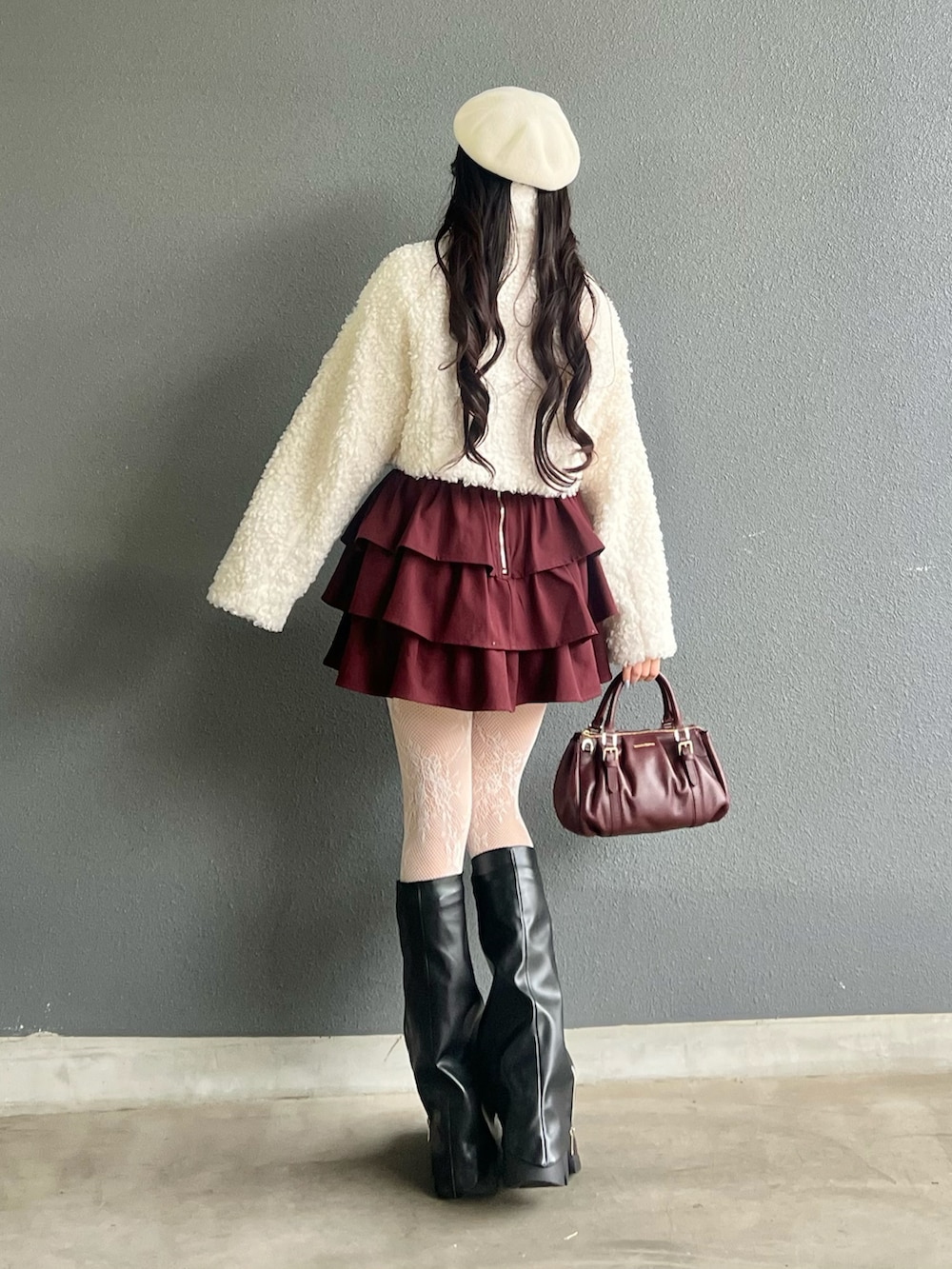 レッド系のバッグ、ブラック系のブーツ、ホワイト系のその他アウターを着用したレディースの秋コーディネートの4枚目の写真