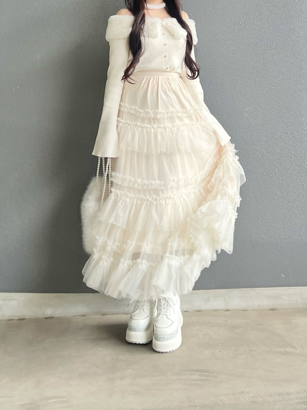 ホワイト系のスカート、ホワイト系のニット/セーター、ピンク系のシューズを着用したレディースの冬コーディネートの3枚目の写真