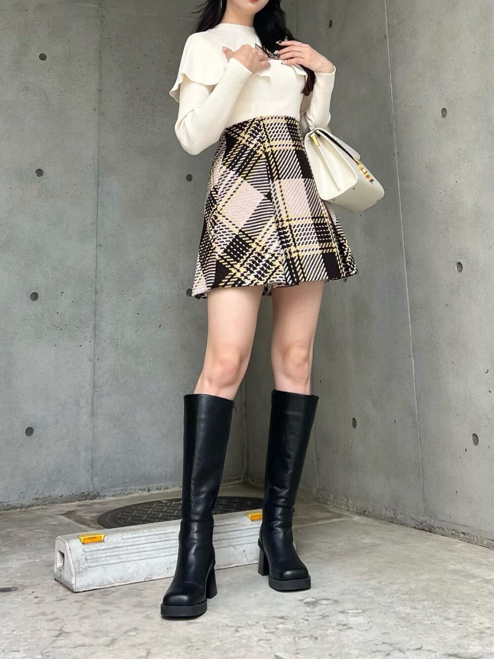 ホワイト系のニット/セーター、ベージュ系のスカート、ブラック系のブーツを着用したレディースの秋コーディネートの3枚目の写真