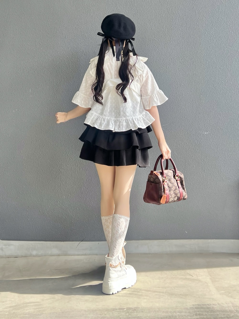 ブラック系のスカート、ホワイト系のベスト、ホワイト系のシャツ/ブラウスを着用したレディースの春コーディネートの4枚目の写真