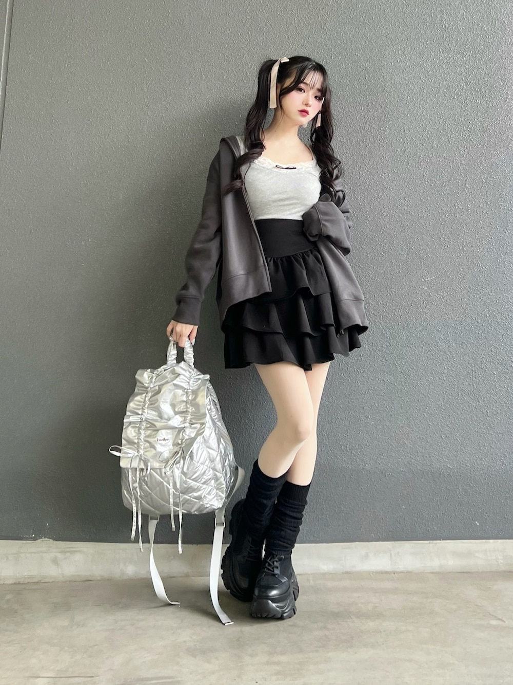 グレー系のパーカー、ブラック系のブーツ、ブラック系のスカートを着用したレディースの冬コーディネートの3枚目の写真