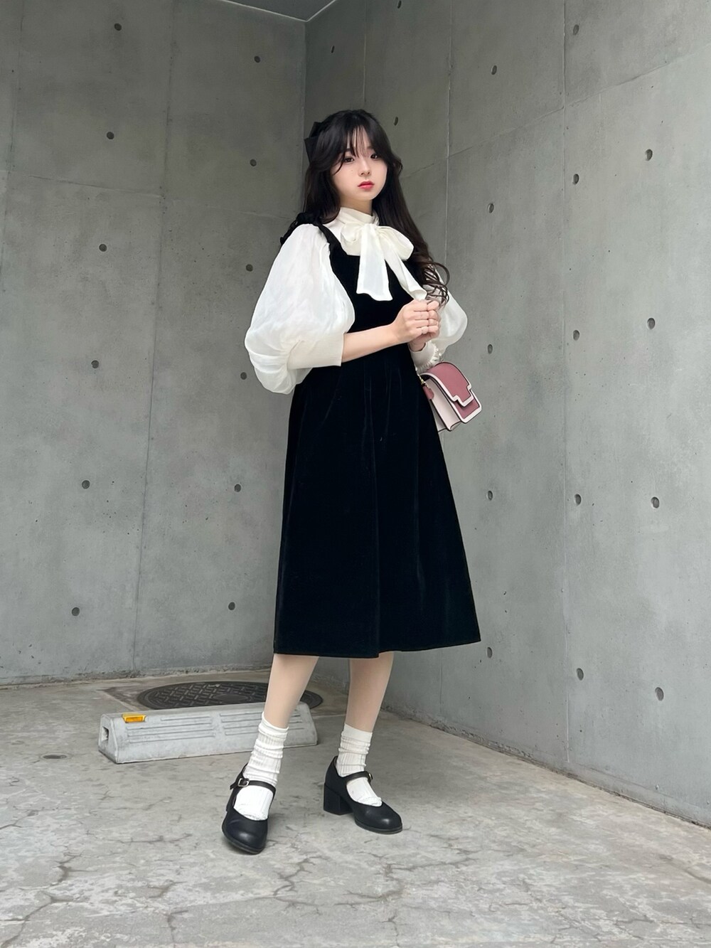 ブラック系のパンプス、ブラック系のジャンパースカート、ホワイト系のシャツ/ブラウスを着用したレディースの冬コーディネートの2枚目の写真