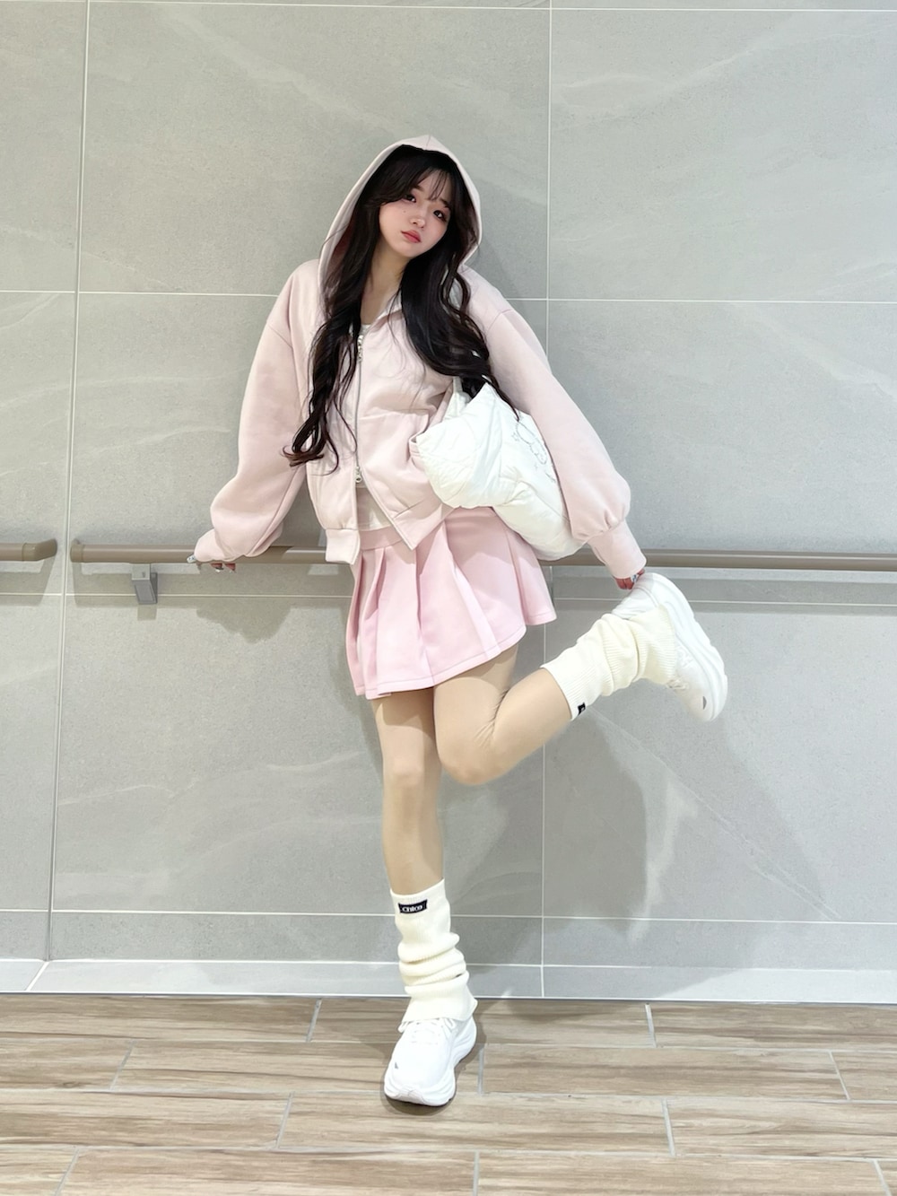 ピンク系のパーカー、ホワイト系のショルダーバッグ、ホワイト系のスニーカーを着用したレディースの春コーディネートの2枚目の写真