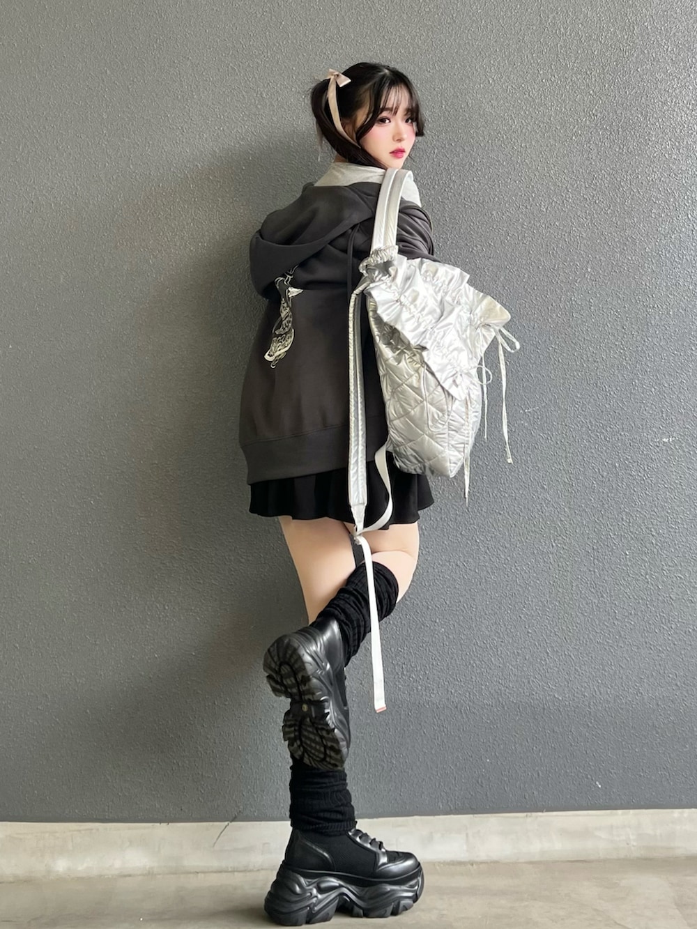 グレー系のパーカー、ブラック系のブーツ、ブラック系のスカートを着用したレディースの冬コーディネートの4枚目の写真