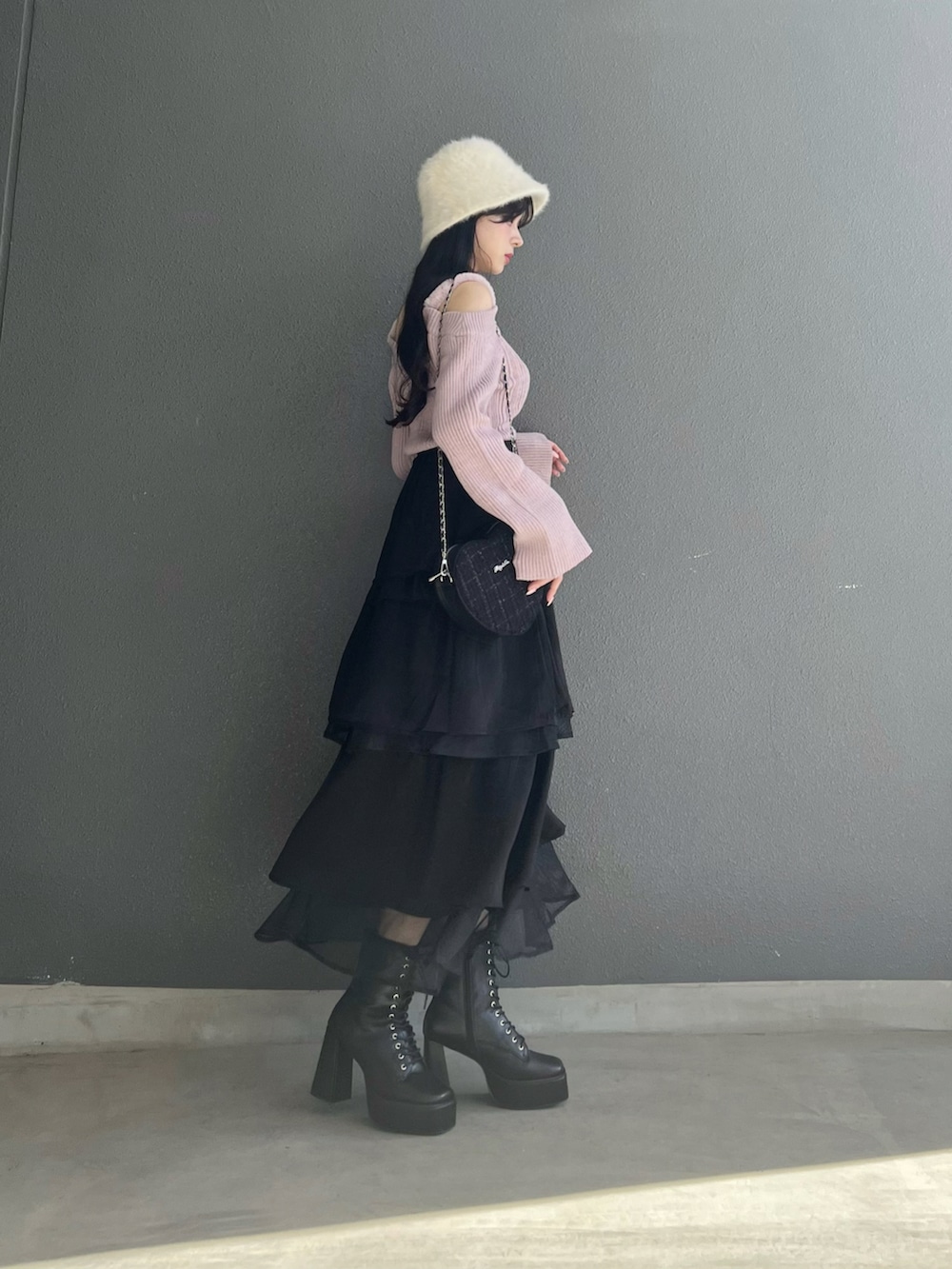 ピンク系のニット/セーター、ブラック系のスカート、ブラック系のブーツを着用したレディースの秋コーディネートの4枚目の写真