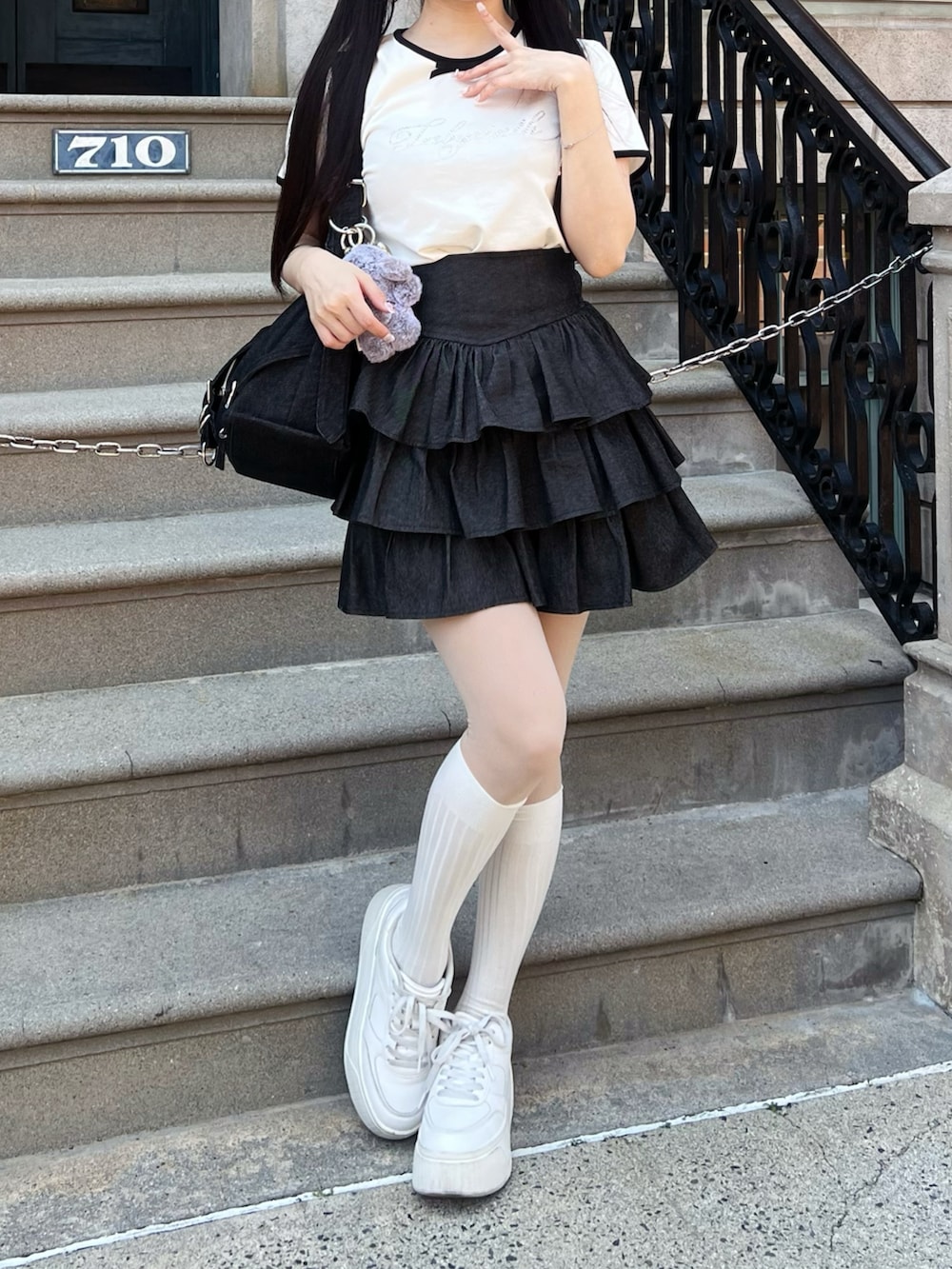 ホワイト系のシューズ、ブラック系のスカート、ブラック系のショルダーバッグを着用したレディースの春コーディネートの3枚目の写真