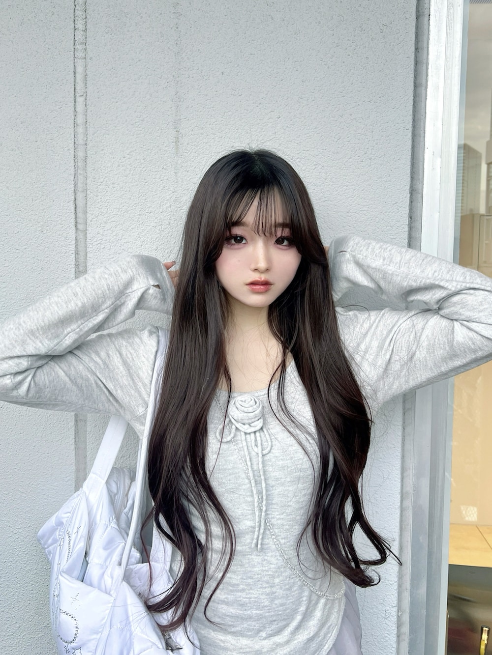 グレー系のニット/セーター、ホワイト系のショルダーバッグ、ホワイト系のスニーカーを着用したレディースの春コーディネートの2枚目の写真