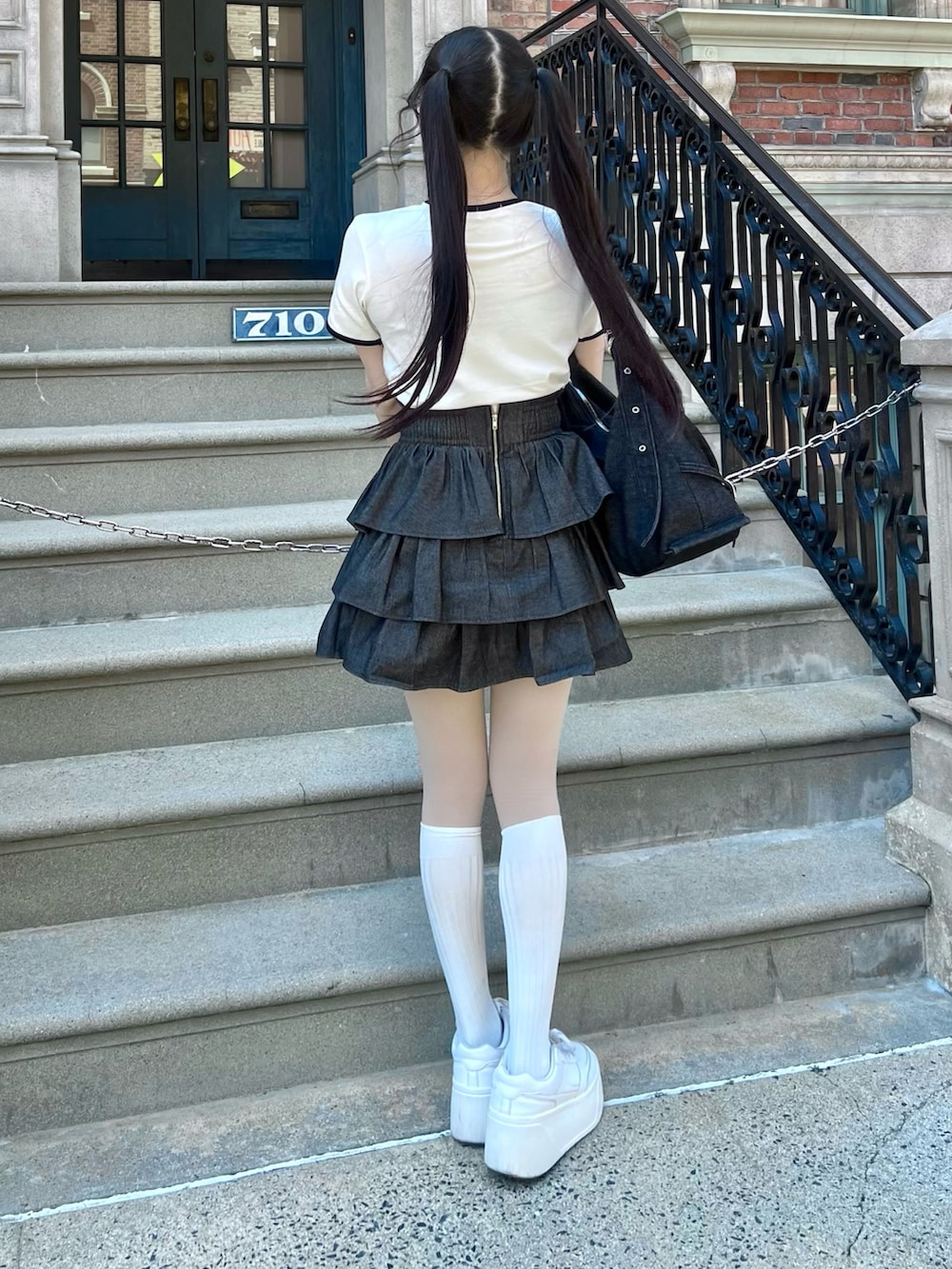 ホワイト系のシューズ、ブラック系のスカート、ブラック系のショルダーバッグを着用したレディースの春コーディネートの5枚目の写真