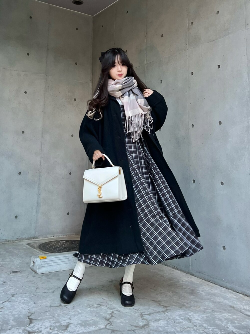 ブラック系のジャンパースカート、ブラック系のパンプス、グレー系のマフラーを着用したレディースの冬コーディネートの2枚目の写真