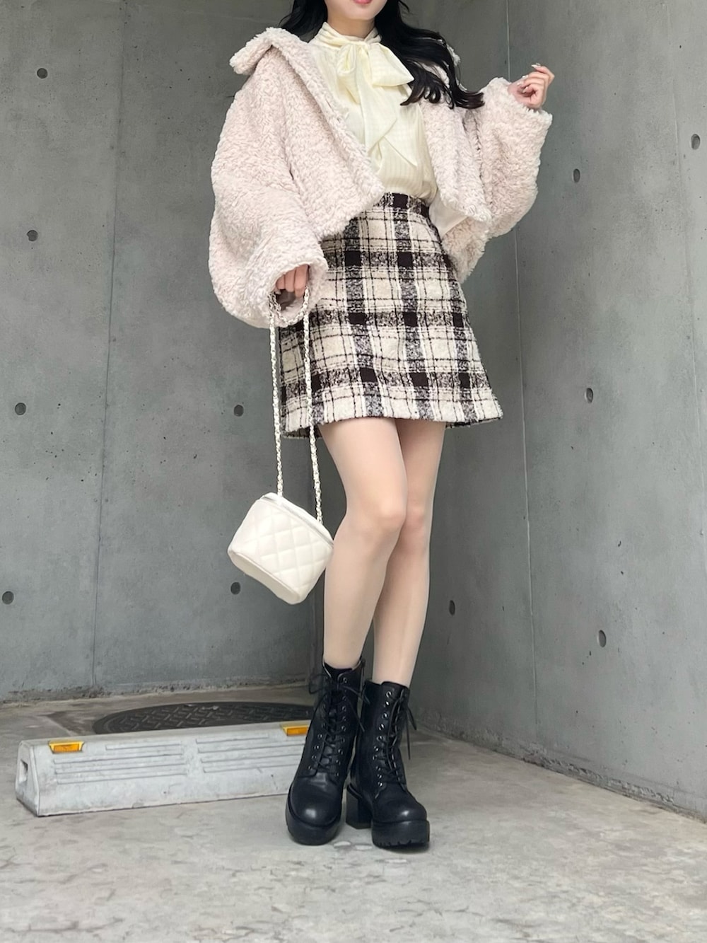 ベージュ系のスカート、ホワイト系のブルゾン、ブラック系のブーツを着用したレディースの冬コーディネートの3枚目の写真