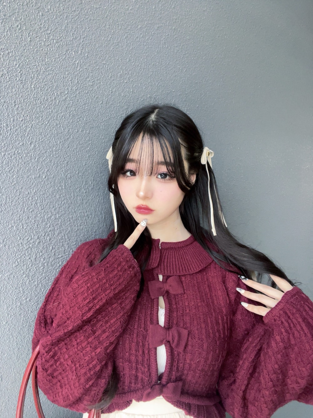 レッド系のバッグ、ホワイト系のスカート、ブラック系のブーツを着用したレディースの秋コーディネートの5枚目の写真