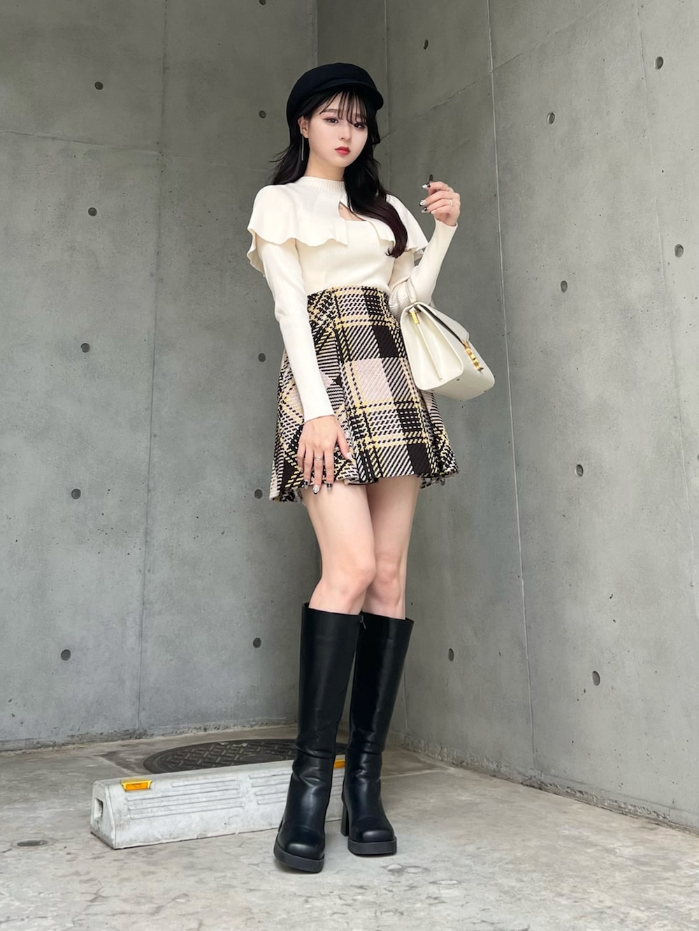 ホワイト系のニット/セーター、ベージュ系のスカート、ブラック系のブーツを着用したレディースの秋コーディネートの2枚目の写真