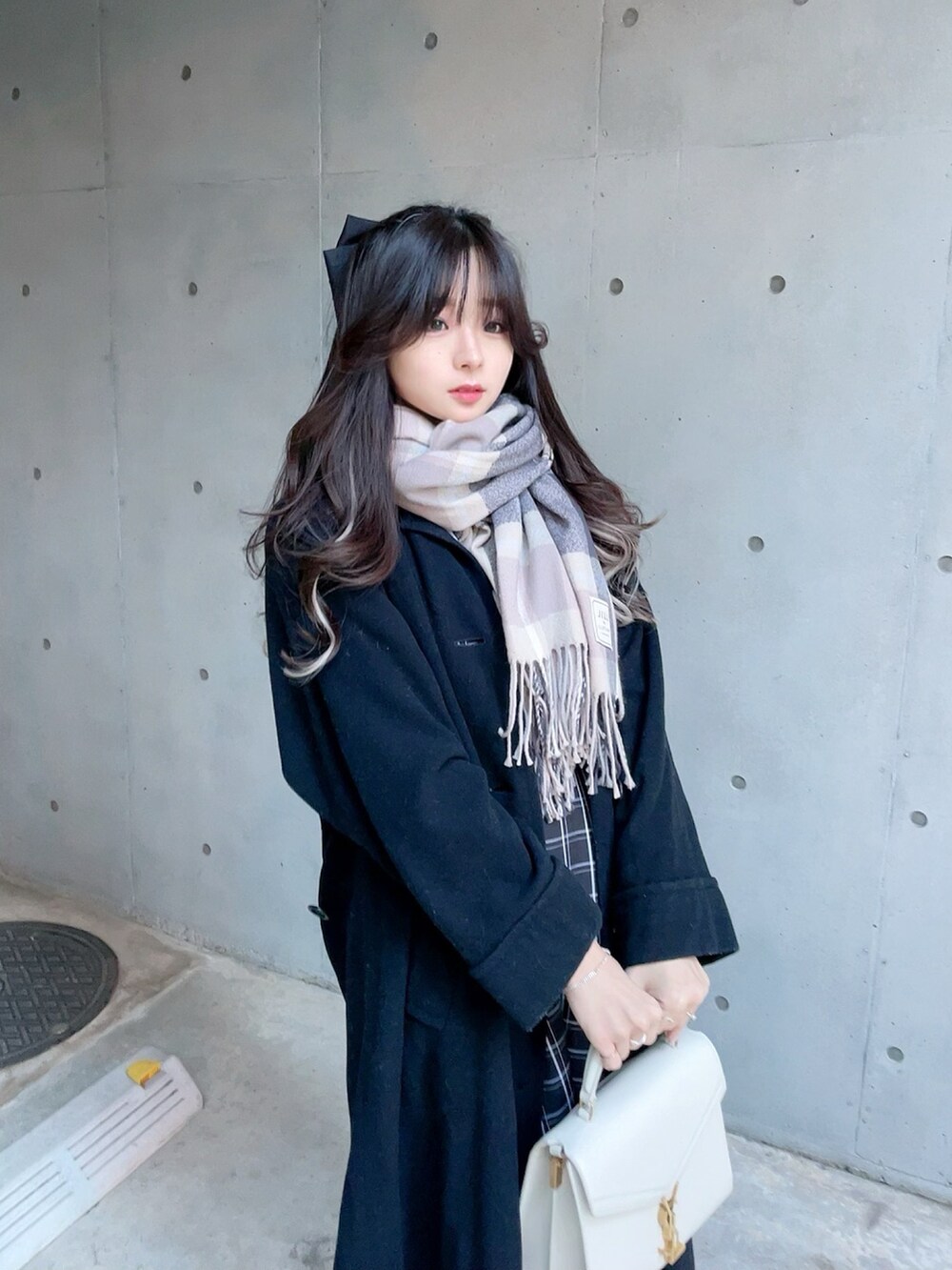 ブラック系のジャンパースカート、ブラック系のパンプス、グレー系のマフラーを着用したレディースの冬コーディネートの5枚目の写真