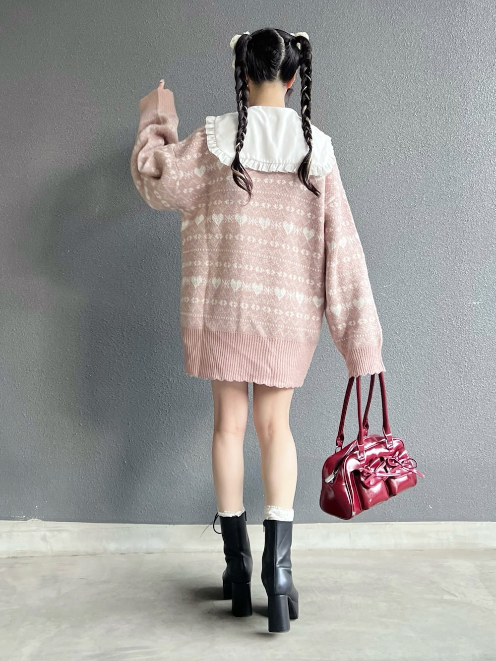 レッド系のバッグ、ブラック系のブーツ、ホワイト系のその他パンツを着用したレディースの秋コーディネートの3枚目の写真