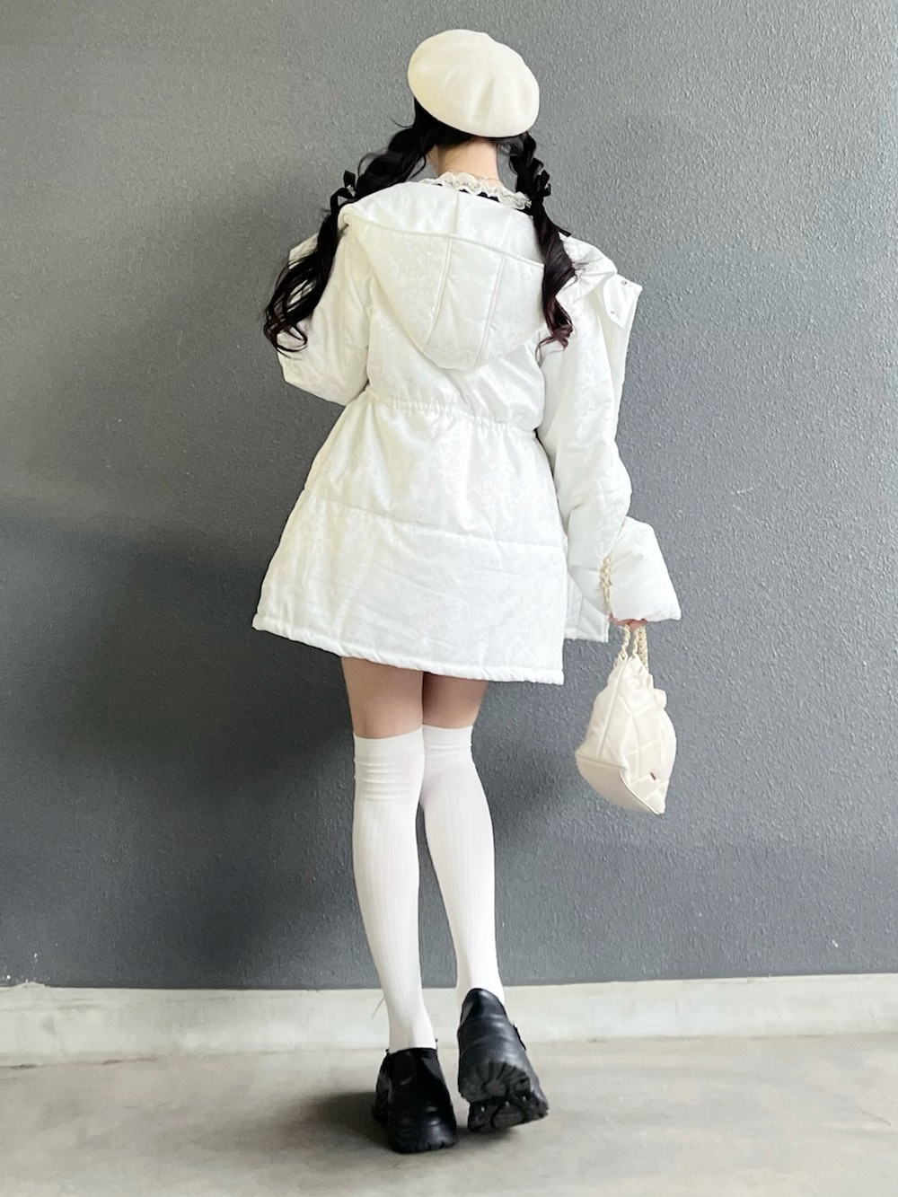 ブラック系のスカート、ブラック系のトップス、ホワイト系のバッグを着用したレディースの冬コーディネートの3枚目の写真