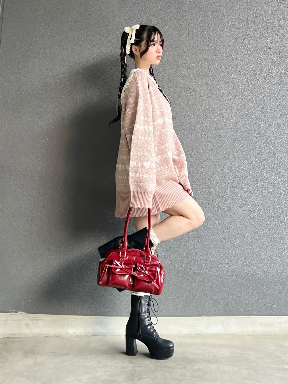 レッド系のバッグ、ブラック系のブーツ、ホワイト系のその他パンツを着用したレディースの秋コーディネートの2枚目の写真