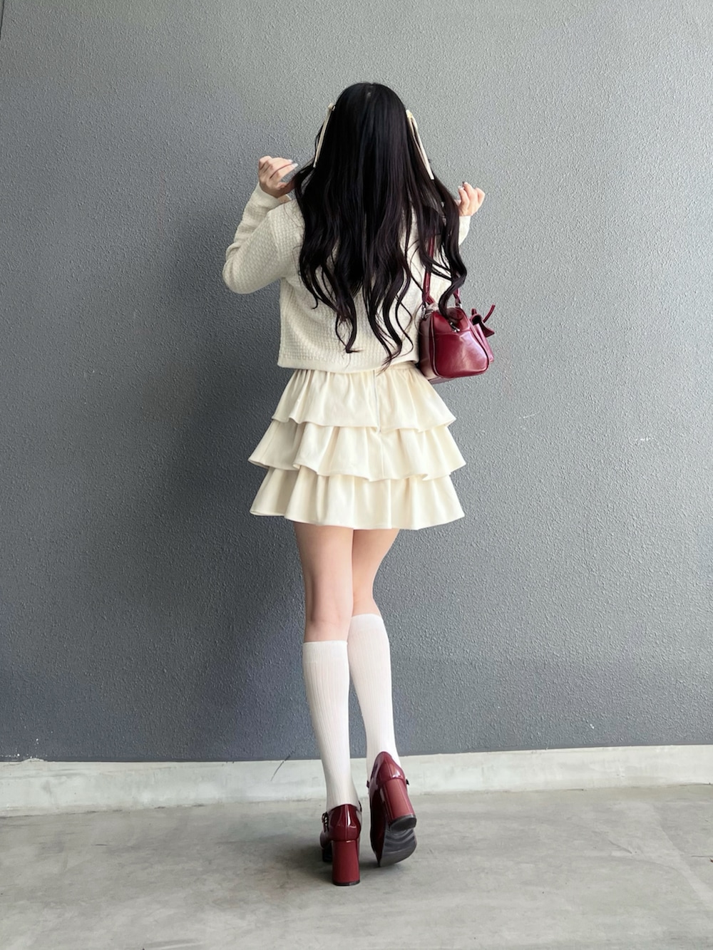 ホワイト系のスカート、ホワイト系のカーディガン/ボレロ、レッド系のパンプスを着用したレディースの秋コーディネートの3枚目の写真