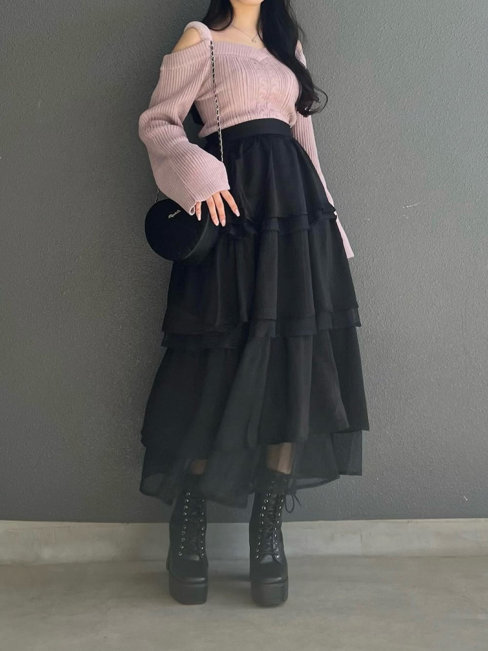 ピンク系のニット/セーター、ブラック系のスカート、ブラック系のブーツを着用したレディースの秋コーディネートの2枚目の写真