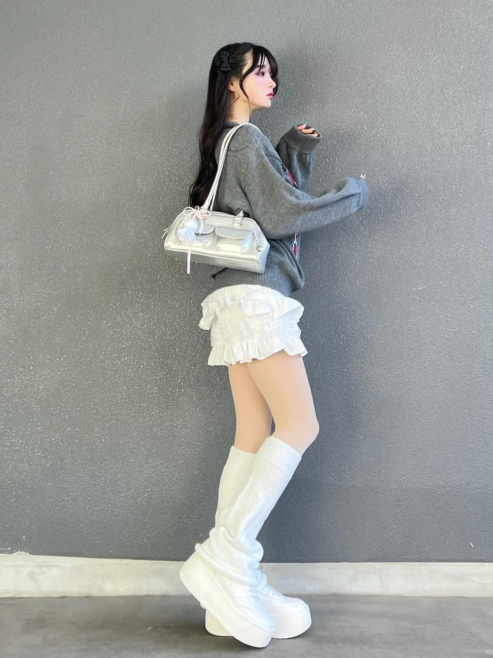 グレー系のニット/セーター、ホワイト系のパンツ、シルバー系のバッグを着用したレディースの冬コーディネートの2枚目の写真