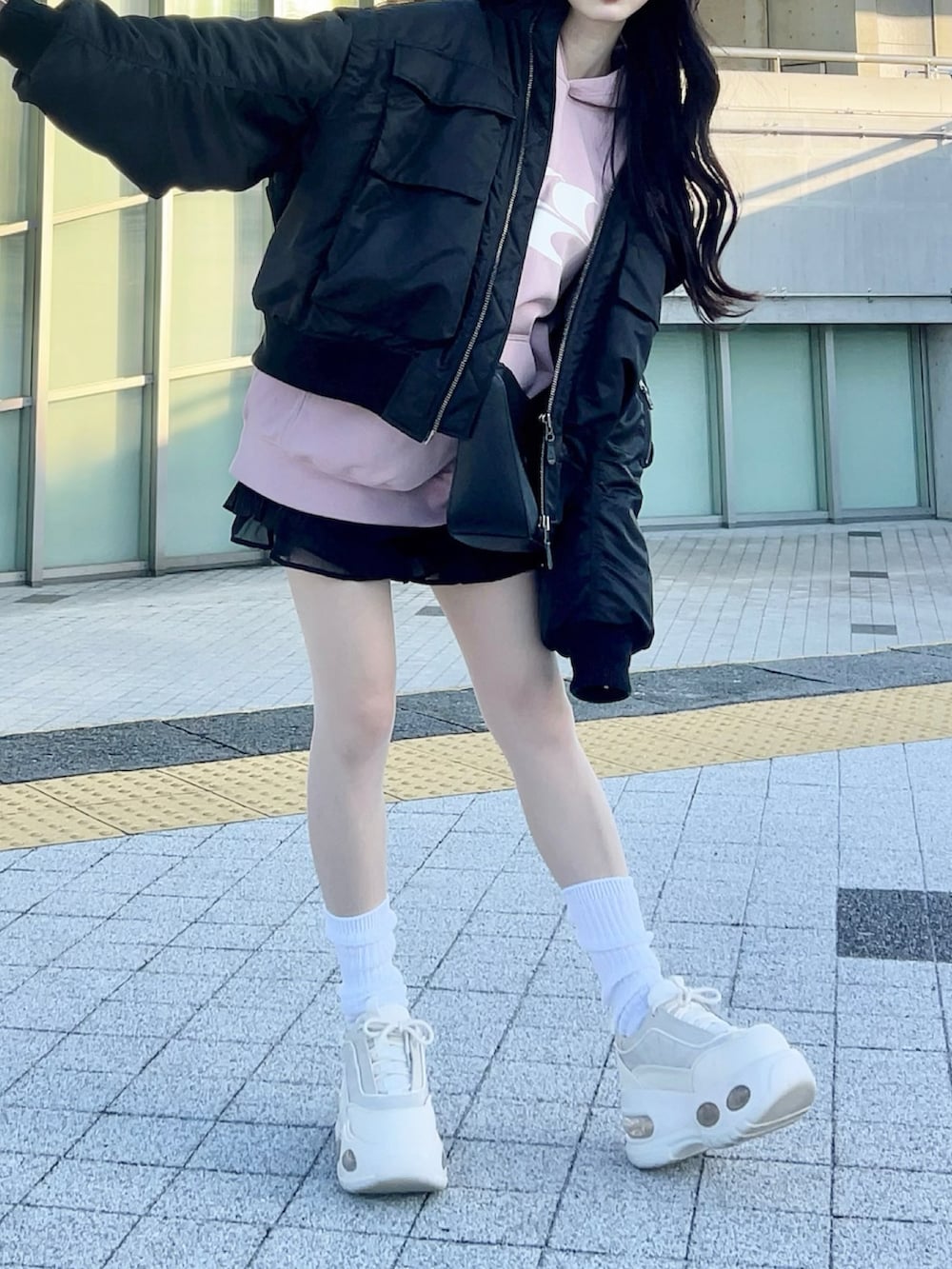 ホワイト系のスニーカー、ブラック系のショルダーバッグ、ピンク系のパーカーを着用したレディースの春コーディネートの3枚目の写真