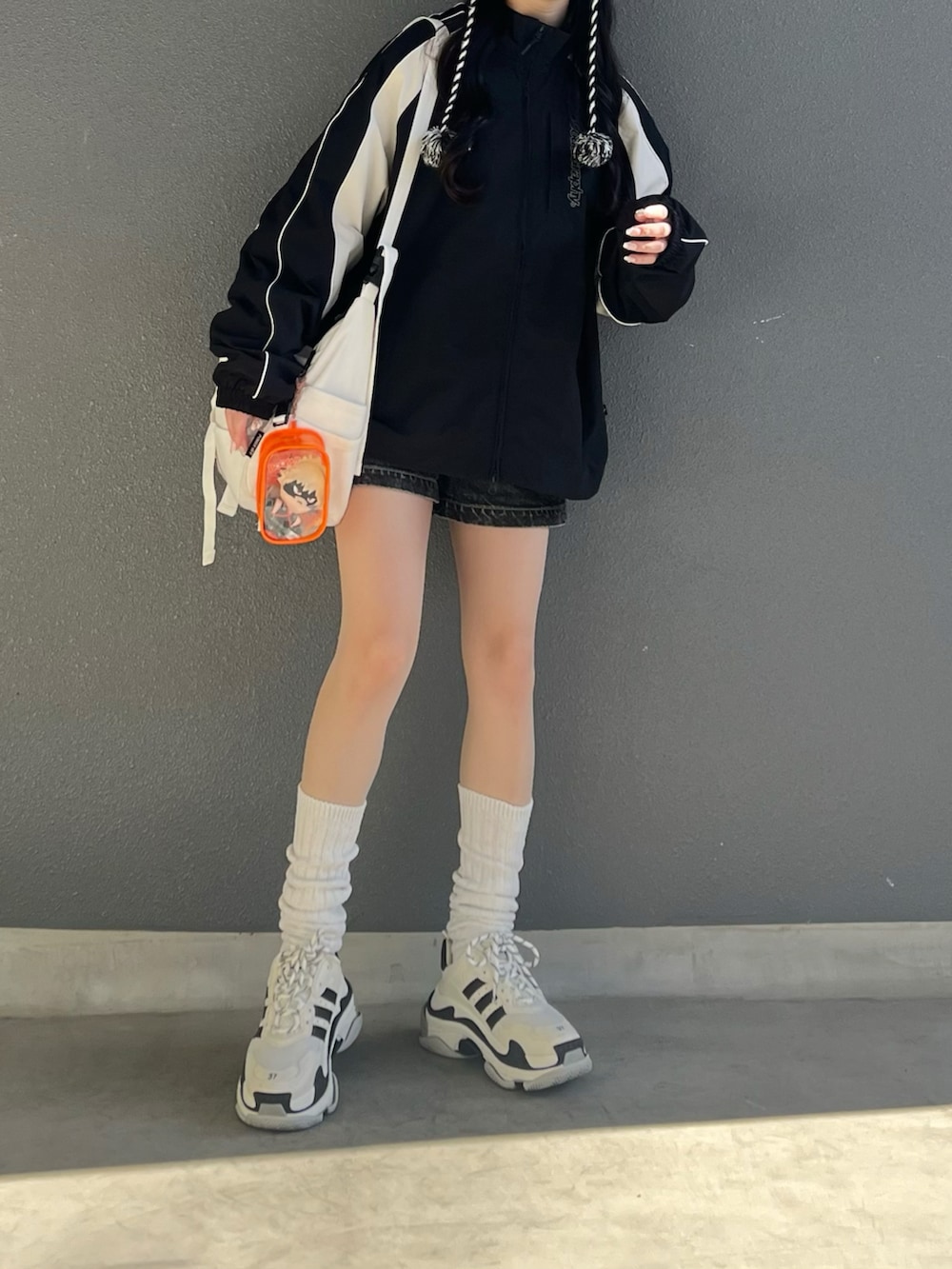 ブラック系のナイロンジャケット、ホワイト系のショルダーバッグ、ホワイト系のシューズを着用したレディースの春コーディネートの4枚目の写真
