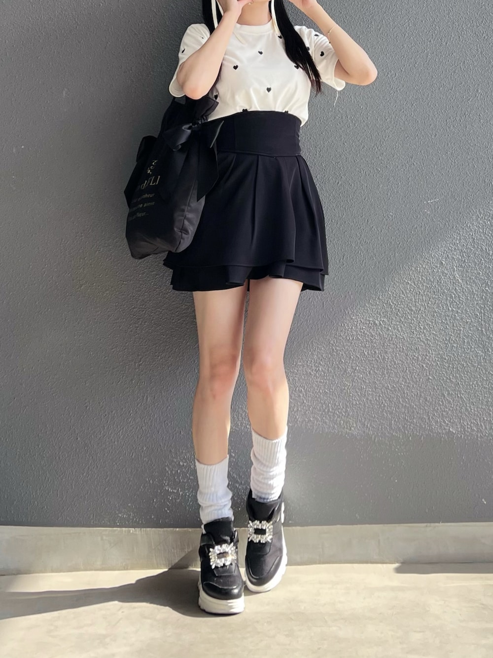 ブラック系のバッグ、ホワイト系のTシャツ/カットソー、ホワイト系のスニーカーを着用したレディースの夏コーディネートの4枚目の写真