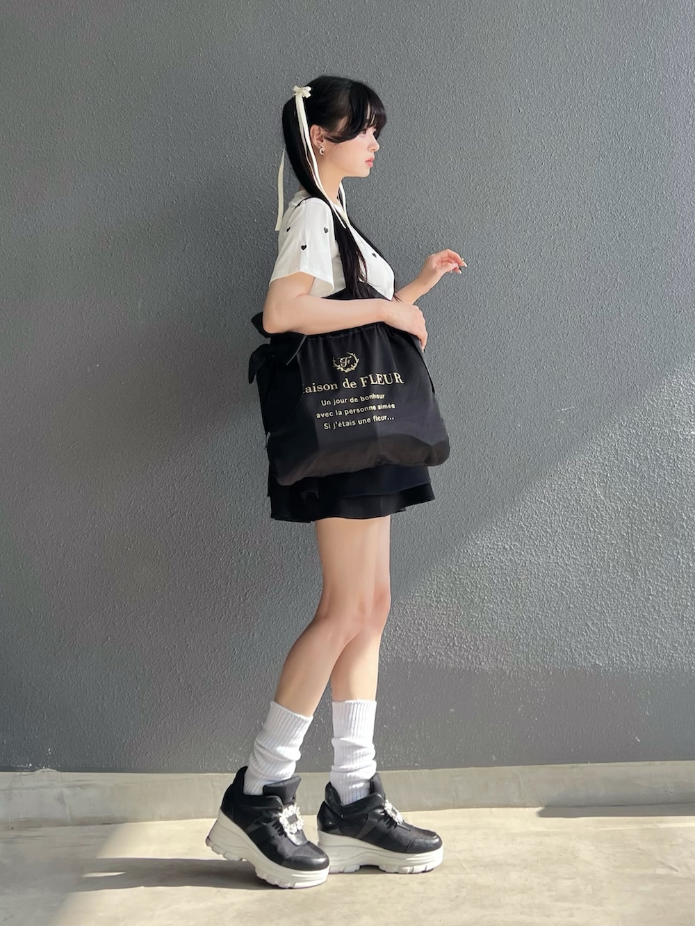 ブラック系のバッグ、ホワイト系のTシャツ/カットソー、ホワイト系のスニーカーを着用したレディースの夏コーディネートの2枚目の写真