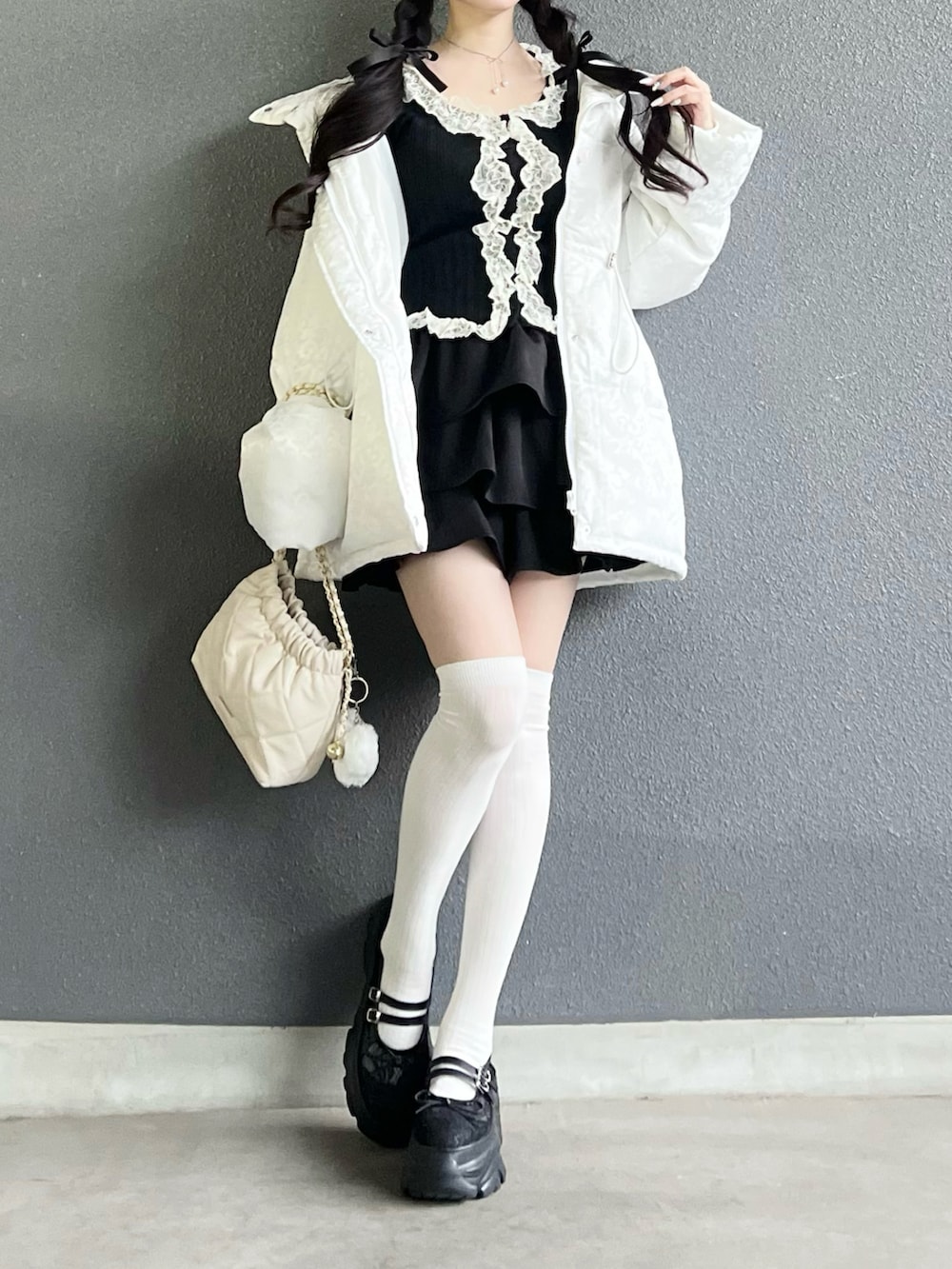 ブラック系のスカート、ブラック系のトップス、ホワイト系のバッグを着用したレディースの冬コーディネートの4枚目の写真