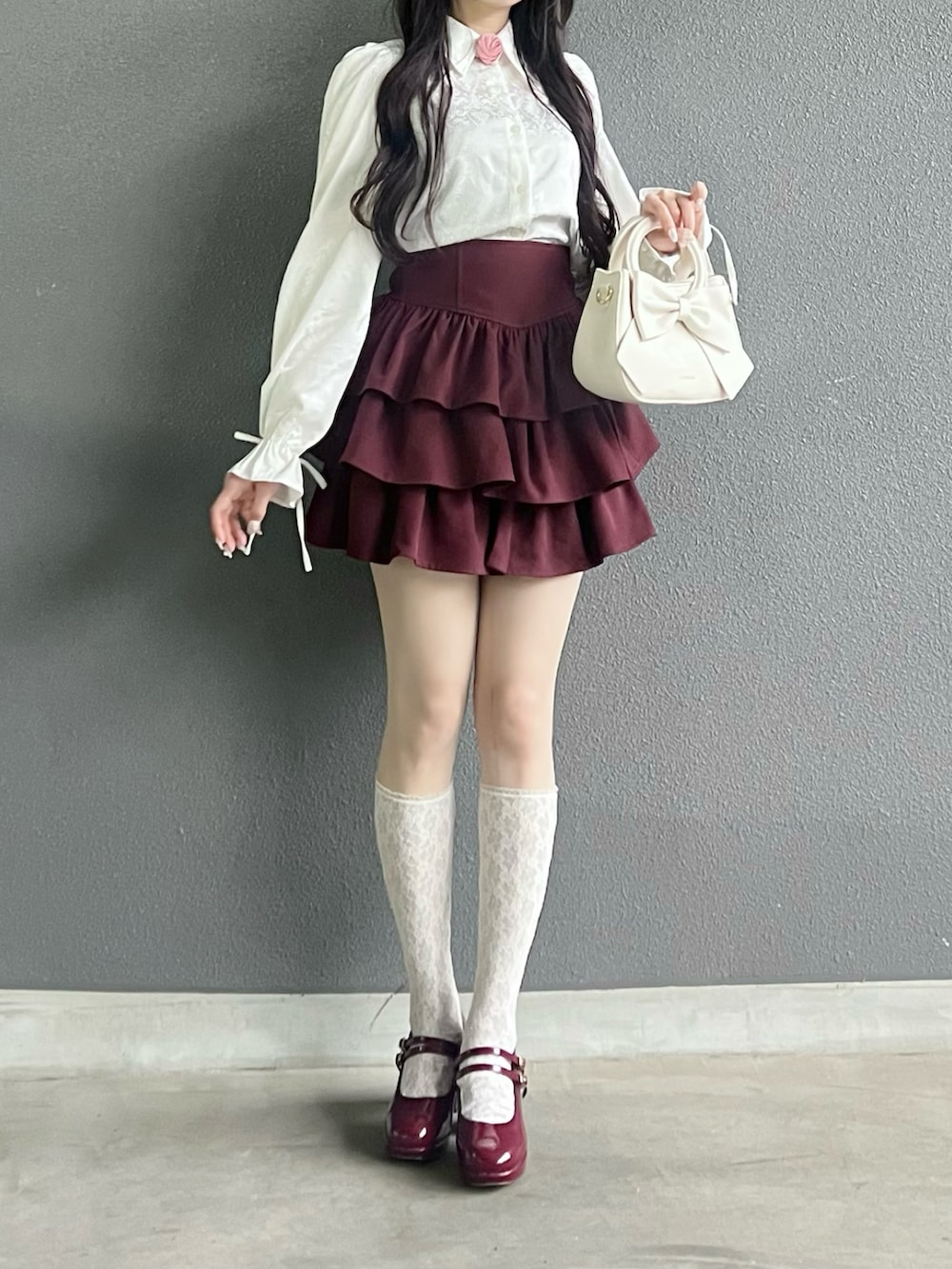 レッド系のパンプス、ホワイト系のバッグ、ホワイト系のシャツ/ブラウスを着用したレディースの秋コーディネートの2枚目の写真