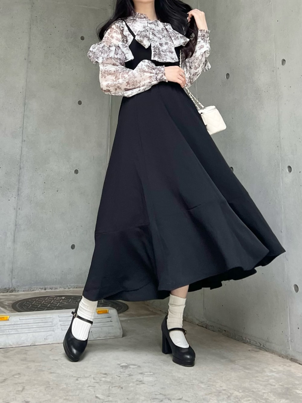 ブラック系のジャンパースカート、ブラック系のパンプス、ホワイト系のシャツ/ブラウスを着用したレディースの秋コーディネートの5枚目の写真